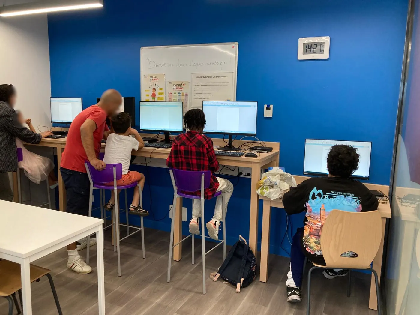 Un parent accompagne son enfant devant l'écran